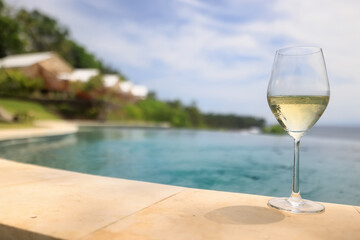a glass of white wine on the background of the pool, relaxing at the hotel