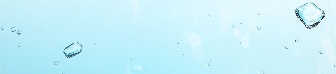 Ice cubes falling in water, light blue background, refreshing drink concept