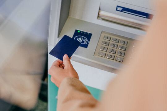 Woman holding card near ATM wireless sensor