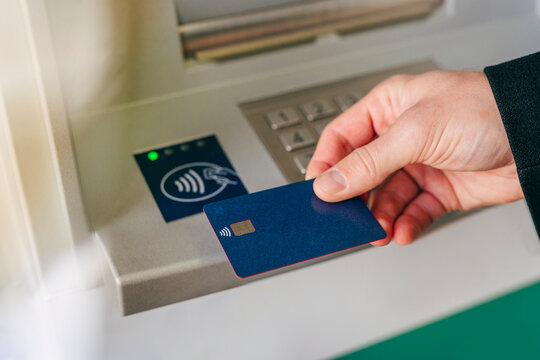 Hand of man tapping card on ATM wireless sensor