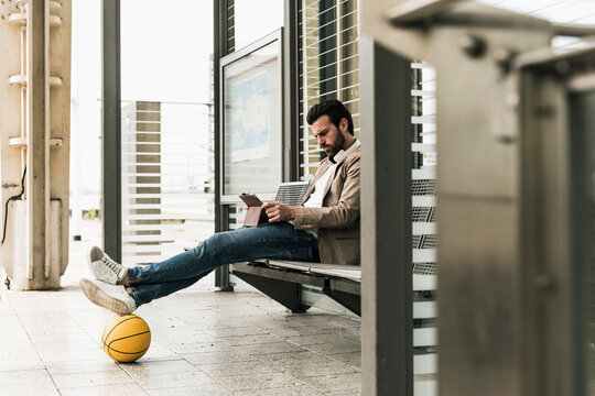 Man with basketball using tablet PC at railway station