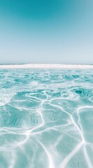 Tranquil turquoise ocean waves gently lap against the sandy shore under a clear blue sky