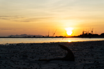 Obraz premium Golden sunset over a tranquil shore with silhouetted fishing boats and calm reflective waters.