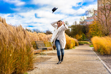 Beautiful middle aged woman walking in city park on windy autumn day. Front view