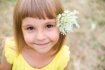 portrait of a smiling little girl with a white flower behind her ear