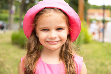 portrait of smiling kid girl in a pink panama hat, summer day