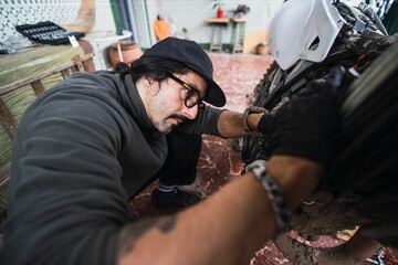 Man repairing motorcycle in garage.