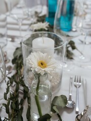 Elegant table setting with white daisy and glassware.