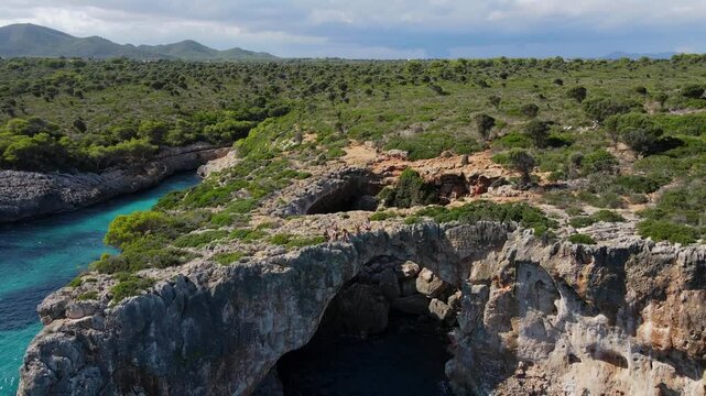 Witness the natural beauty of Cala Varques in Porto Cristo, Majorca. This serene location features dramatic cliffs, crystal-clear waters, and lush greenery for an unforgettable experience.
