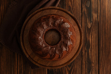 Chocolate cake with chocolate icing on dark wooden table. Low key. Top view