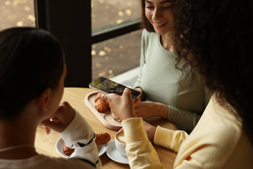 Woman taking picture of coffee drinks during meeting with her friends in cafe, closeup