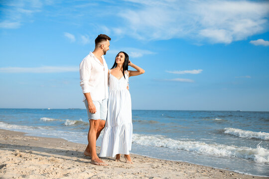 Happy young couple at beach on sunny day - Powered by Adobe