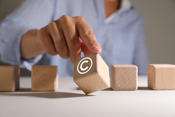 License. Man choosing wooden cube with copyright symbol at table, closeup