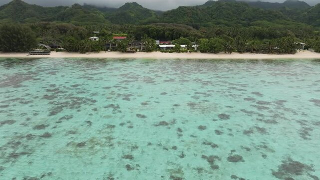 Aerial tracking left of coastal fringing reef protecting waters in Rarotonga Cook Islands, tropical paradise