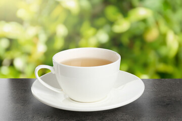 Green tea in cup on grey textured table outdoors