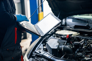 Serviceman with laptop checks car software in car service