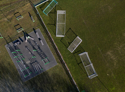 outdoor gym in the yard with stone sandstone wall and flexible rubber floor. sports ground with fitness aids, parallel bars, crossbars, rib tables made of metal . drone, top, point of view, high angle