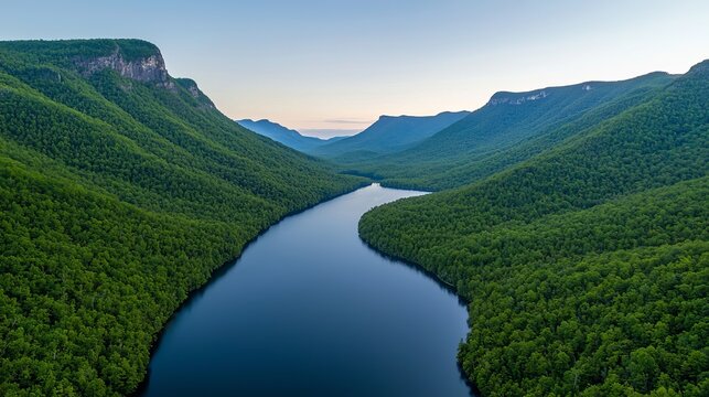 In the morning light, a breathtaking view of emerald mountains and a serene lake stretches out, framed by the hues of a rising sun. This picturesque setting emphasizes a critical watershed forest,