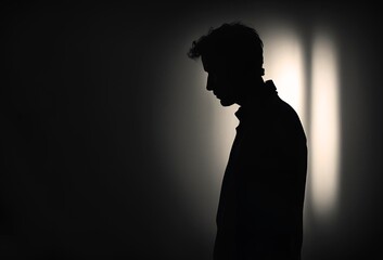暗い空間で落ち込んでいる男の横顔のシルエット