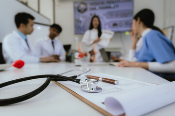 A diverse team of health care professionals, including doctors and nurses, sit and talk in a hospital office. The team works together to provide expert medical care and support to patients.