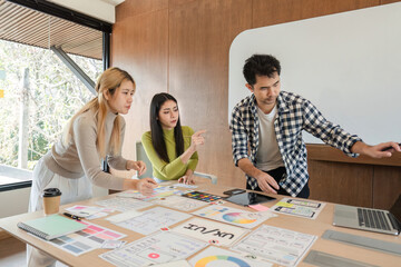 Diverse team of designers collaborating on UX UI project in modern office.
