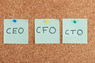 Business leadership team notes showing CEO CFO and CTO roles pinned to a corkboard A clear visual representation of corporate structure