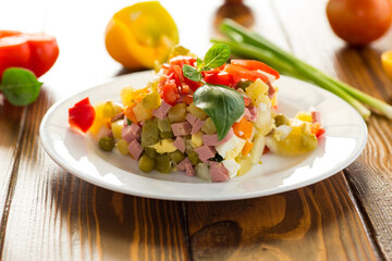 vegetable salad of boiled vegetables, with peas, sausage, sweet pepper. On a wooden table