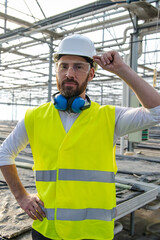 Smiling caucasian bearded engineer in protective glasses at the construction site