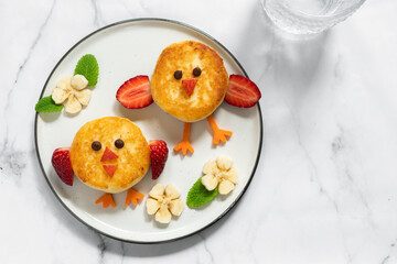 A plate of food with two birds made out of doughnuts and strawberries
