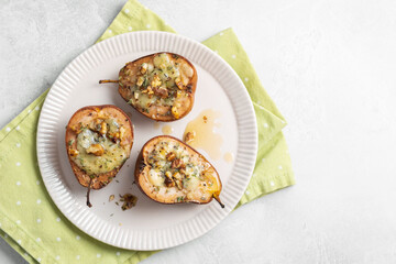 Three pears with cheese and walnuts on a white plate