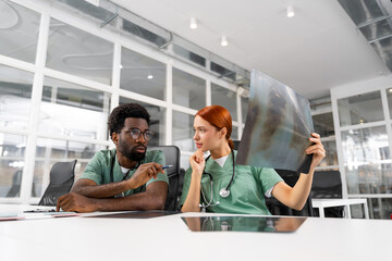 Fototapeta premium Redhead woman and male doctor having conversation about patient’s bone care