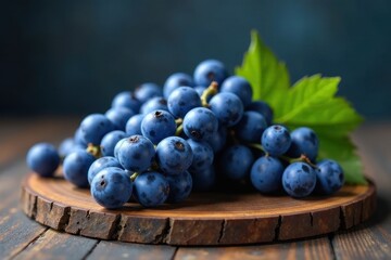 Fototapeta premium A cluster of ripe, dark-blue grapes rests on a rustic wooden board, showcasing their vibrant color and natural texture, enhanced by a few fresh leaves.