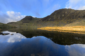 Pavey Ark reflections in Stickle Tarn with dramatic blue sky. Lake District, UK.
