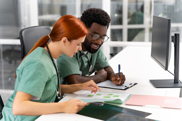 Naklejka premium Doctor and nurse discuss treatment plan for patient sitting at table in clinic