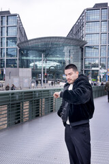 Young man in a winter coat checking his watch in front of Berlin’s Hauptbahnhof. A modern travel and commuting scene