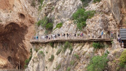 Tourists walking on a wooden bridge in a scenic canyon