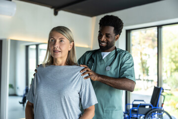 Fototapeta premium African american male doctor working on correction of female patients posture