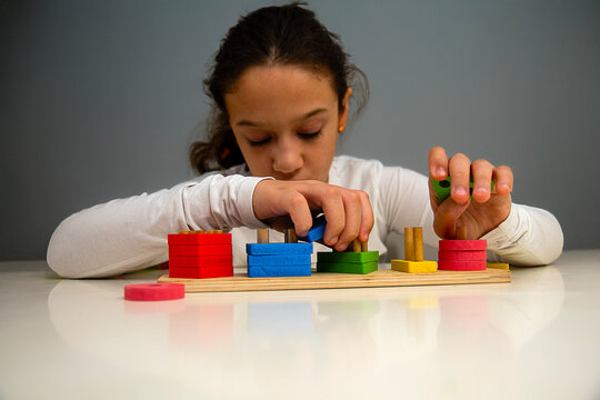 Focus on fingers as a child exercises brain development through didactic play, stacking shapes to enhance cognitive and motor skills.