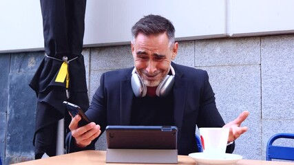 Sad businessman reacting to bad news on smartphone at cafe