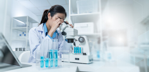 Asian Researcher using a microscope in the clinical lab.Female Researcher working in the clinical...