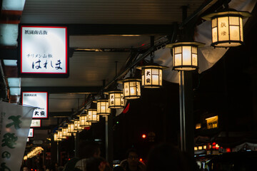 street in Japan, characterized by a series of illuminated lanterns and signs with Japanese text