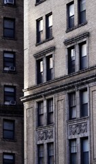 Vertical view of two multi-story brick buildings with air conditioners in windows