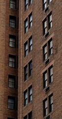 Fototapeta premium Vertical closeup view of a section of a brown brick building featuring numerous windows