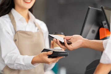 Customer making payment with smartphone at a cafe checkout