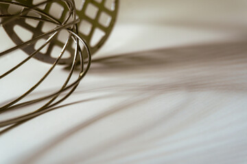 Creative arrangement of a metallic whisk and perforated kitchen tool casting artistic shadows on a...