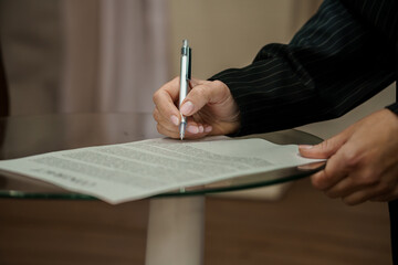 Professional Hand Signing a Document on a Glass Table