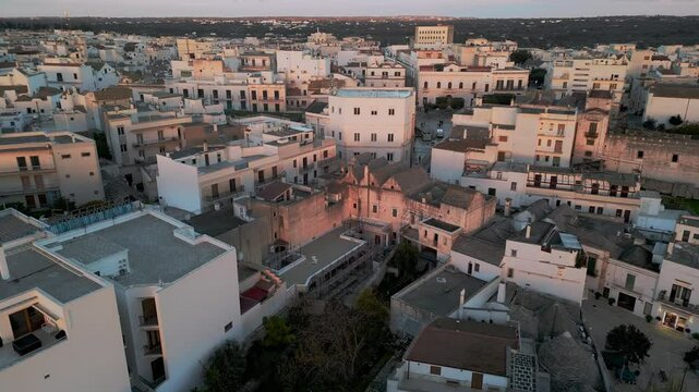 flight over the center of Alberobello. city is famous not only for amazing architecture of the Truli houses, but also for true architecture of Italy. white houses with tiled roofs in the setting sun