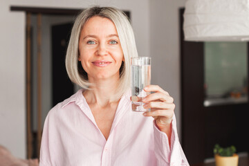adult woman holding glass of pure mineral water at home