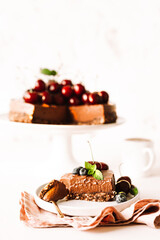 One piece of chocolate cheesecake decorated with fresh cherries, blueberries and a whole pie