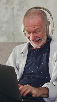An elderly man actively types on a laptop keyboard, leaving a comment on a social media. An adult hater on social networks.Cheerful old man follower writes social media comment on laptop.